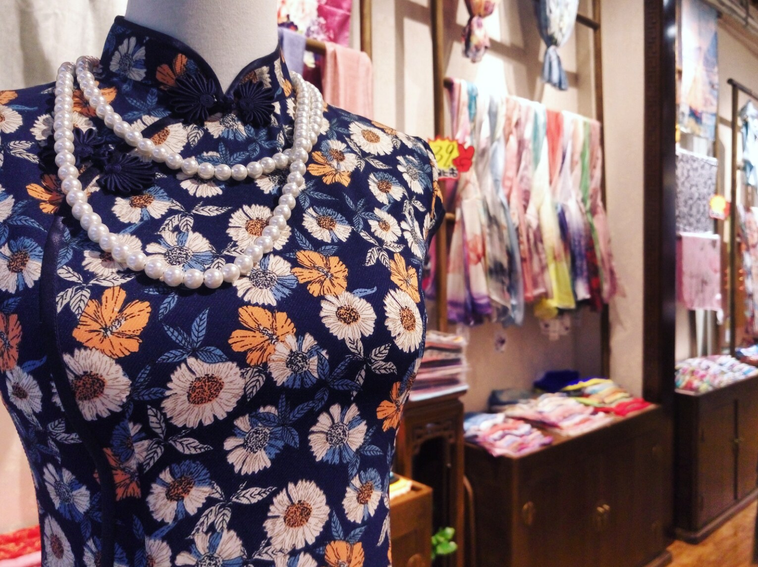 A floral qipao displayed among colorful fabrics in a Shanghai fashion shop