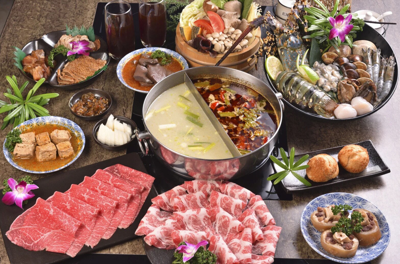 A generous shared Chinese hot-pot meal with meats, seafood, vegetables, and side dishes